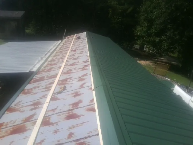 Old rusted panels beside newly installed green metal roofing — Wind Damage Roof Repair by Roofing Brothers in Cape Neddick