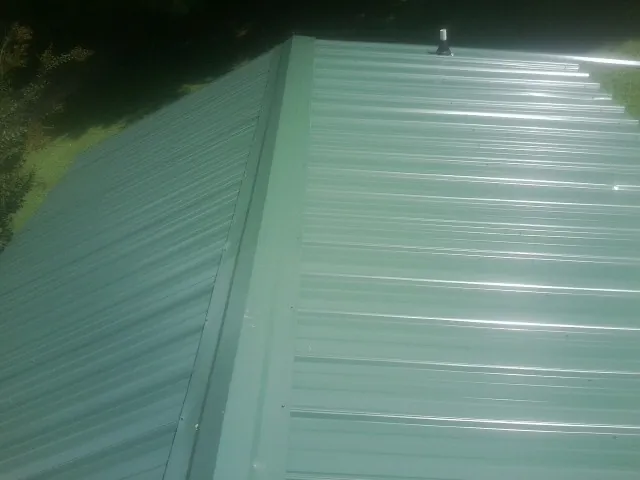 New green metal panels meeting at the ridge of a roof — Flat Roof Repair work by our crew in Cape Neddick