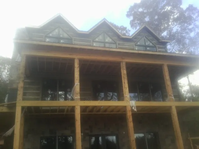 Dormers and porch framing on a large log home under construction — Roof Coating work by our crew in Cape Neddick