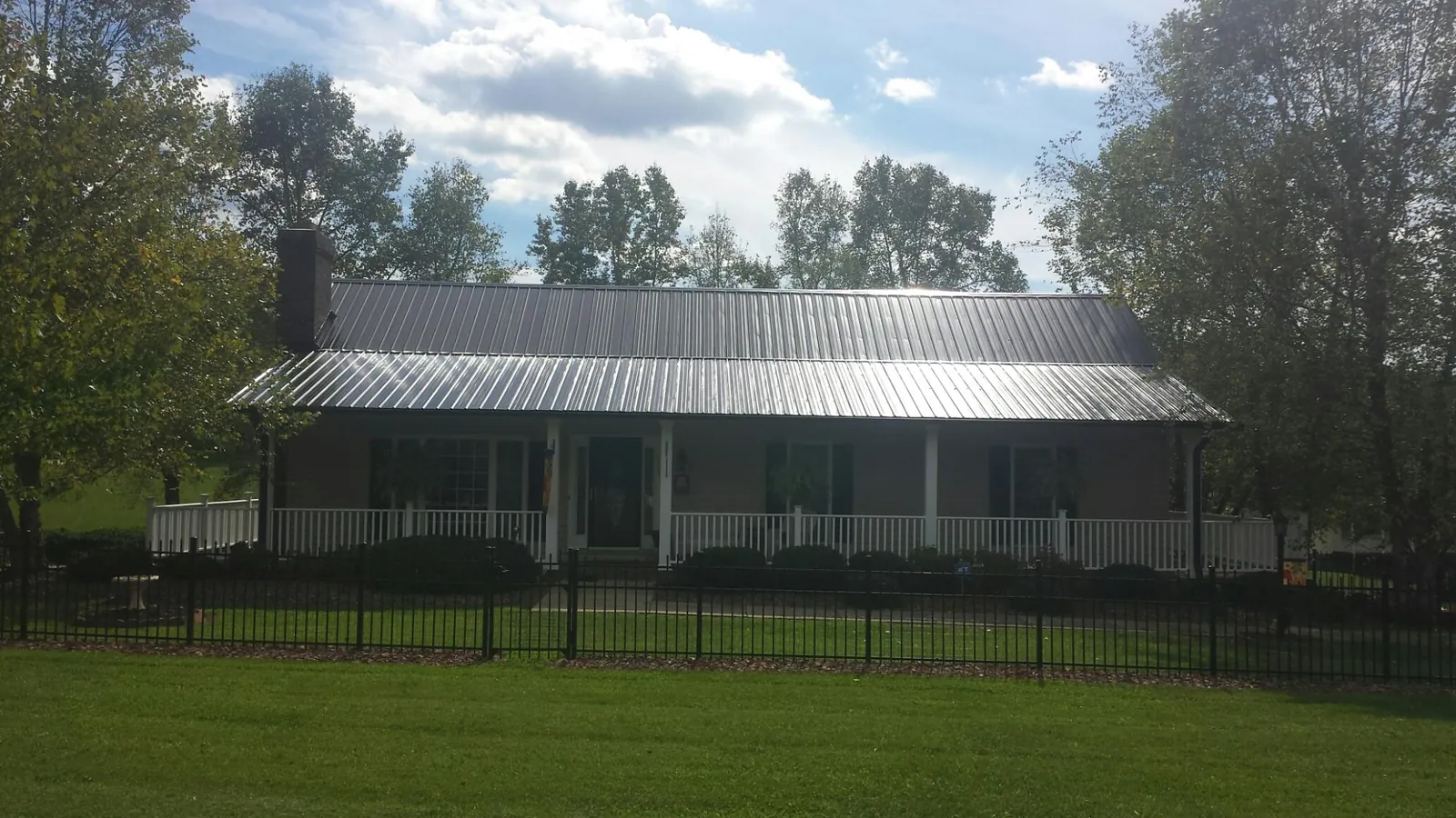 Gray metal roof on a brick ranch with a full width front porch — Gutter Guard Installation work by our crew in Cape Neddick