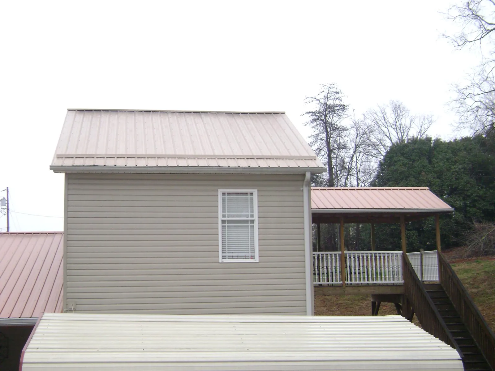 Tan metal roofs on a two story addition and attached porch, from a Roof Replacement job in Cape Neddick