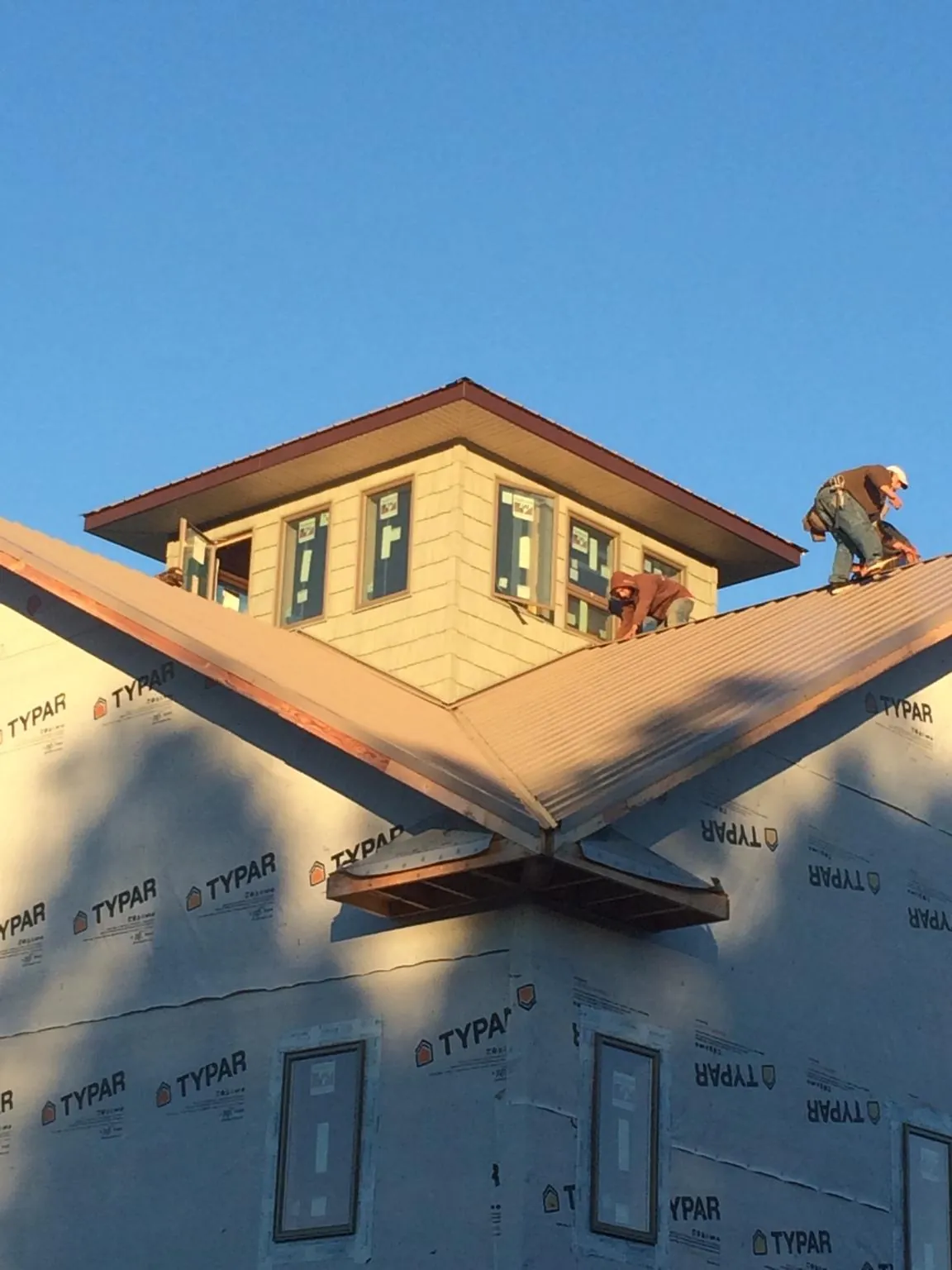 Roofers working around a rooftop cupola on a new metal roof at sunset — Roof Waterproofing in Cape Neddick by Roofing Brothers